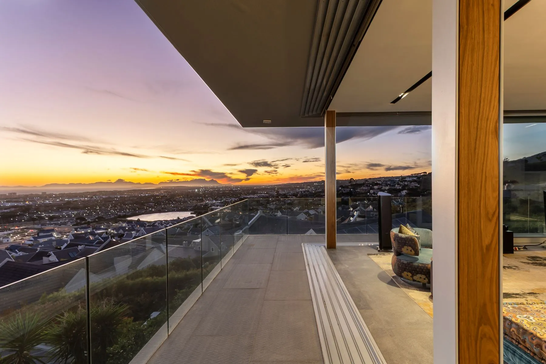 Covered upper balcony of the former property, overlooking the city and coast at sunset